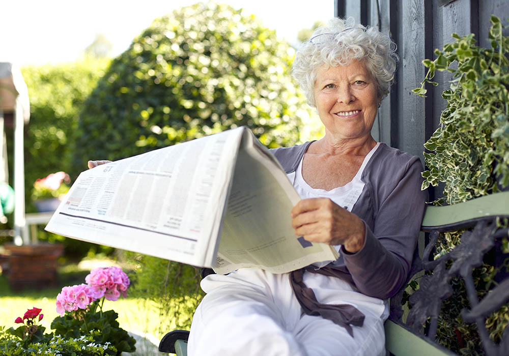 elder woman reading the morning newspaper